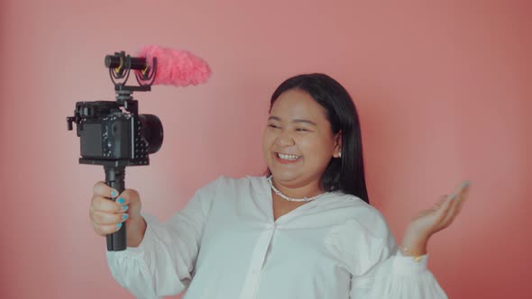 Young Woman Vlogger Recording Broadcast in Slow Motion on a Pink Background alt