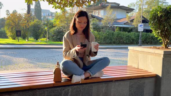 Woman With Coffee and Smartphone in the City