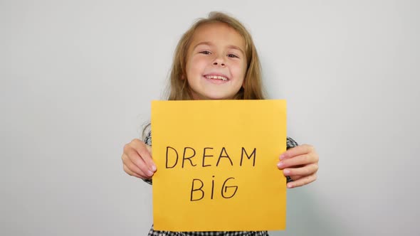 Smiling teenage girl shows into the camera phrase dream big alt