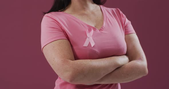 Woman with arms crossed wearing pink breast cancer awareness ribbon on t-shirt alt
