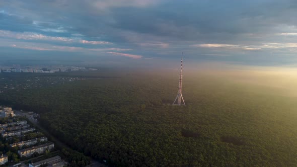 Sunrise aerial view on tv tower in cloudy forest