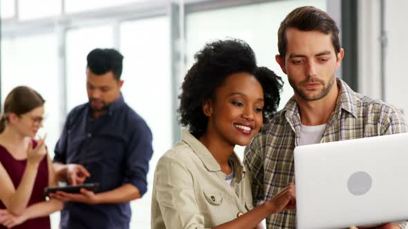 Business executives discussing over laptop alt