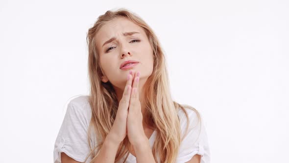Young Beautiful Caucasian Blonde Girl Begging Saying Please Praying on White Background in alt