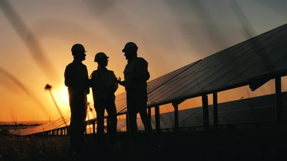 Sunset at the Solar Power Station with a Group of Specialists Talking alt