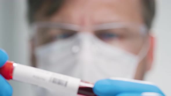Male Doctor in Face Mask Analyzing Blood Sample alt