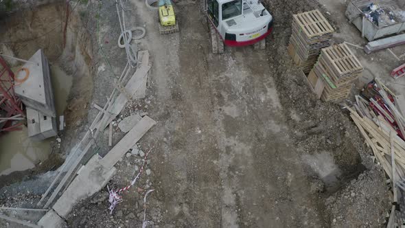 Worker walking past an excavator at a construction site,overhead shot. alt