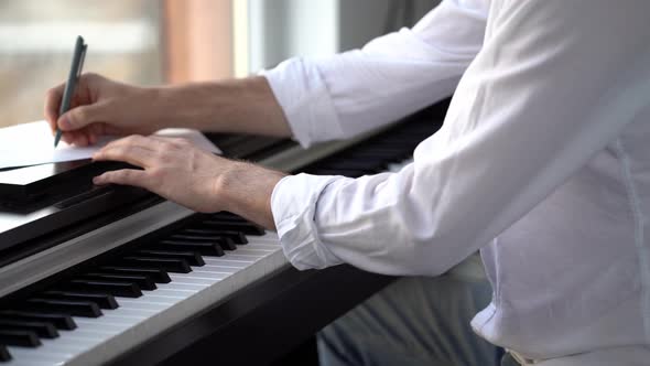 The composer plays the piano composes music and writes it down with notes alt