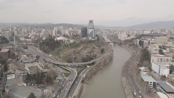 Flying over Kura river in Tbilisi. Beautiful aerial view of Baratashvili bridge alt