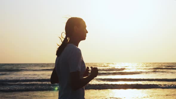 Fit Sporty Woman is Jogging on the Beach at Sunset