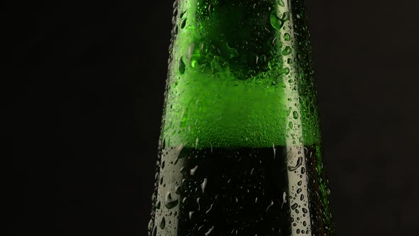 Drop of condensation drips on beer bottle glass. Water drops falling down alt