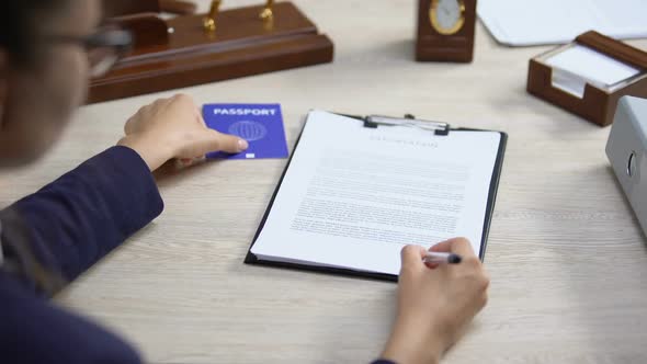 Employee Signing Deportation Document Holding Blue Passport, International Law alt