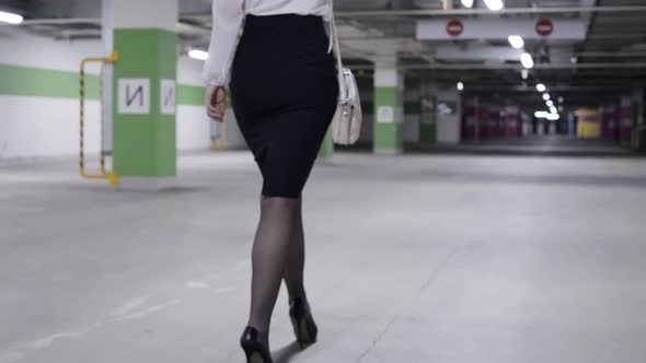 Back View of Woman Walk with Pony Tail White Shirt and Black Skirt in Garage