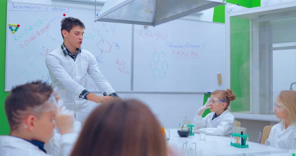 Teacher and Students Doing Science Experiment in School Classroom alt