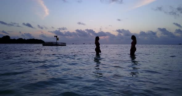Sexy beauty models travelling spending quality time at the beach on clean white sand and blue background alt