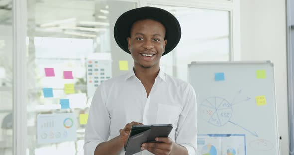 African American in Black Hat and White Shirt Looking Into Camera in Contemporary Glass Office alt