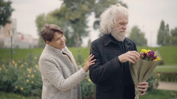Elegant Senior Man Waiting with Bouquet of Flowers As Happy Woman Surprising Husband alt