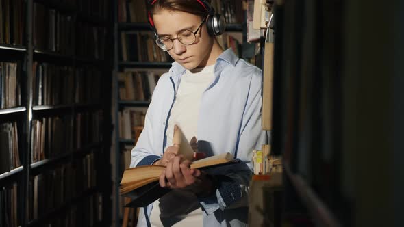 A Teenager in a Library Reads a Book