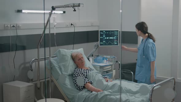 Medical Assistant Looking at Heart Rate Monitor While Patient Sleeping alt