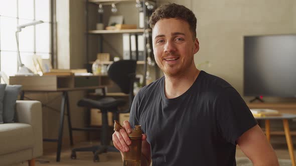 Sweating Man in Gray Outfit Poses After Workout at Home in His Spacious and Sunny Living Room with alt