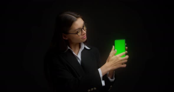 Business Lady in Glasses Shows Vertical Green Phone Screen for Copying alt