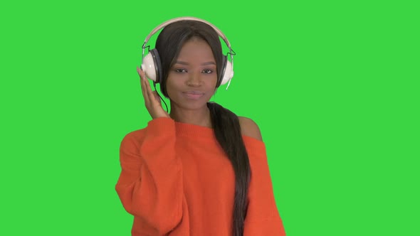 Young African American Woman with Headphones Listening and Grooving To Music on a Green Screen alt