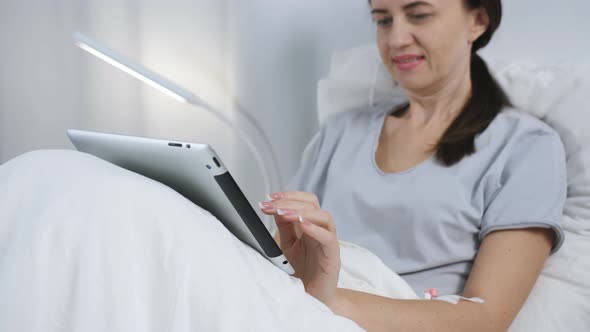 Patient Using Digital Tablet in Hospital Bed