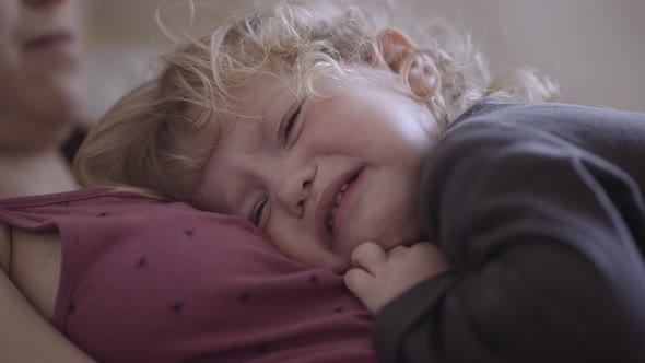 a disgruntled child lies on his mother's chest alt