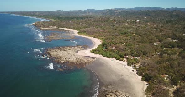 Aerial drone view of the beach, rocks and tide pools in Playa Palada, Guiones, Nosara, Costa Rica. alt