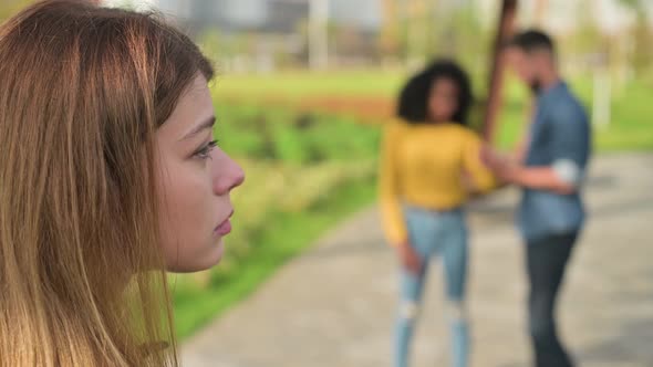 Young woman is sad. out of focus man and a black woman communicate very closely alt