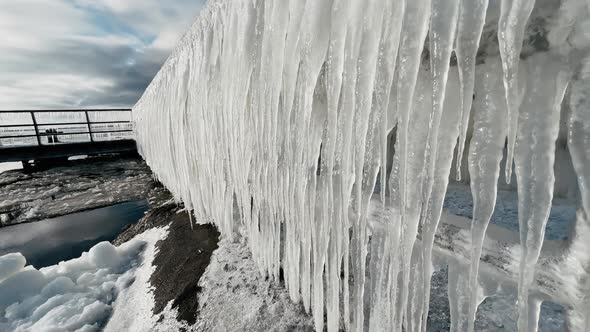 Huge Scary Icicles Hanging From Metal Railing on Sunny Winter Day alt