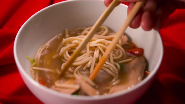 Closeup View on Chinese Cuisine Soup Hand Stirring with Chinese Chopsticks