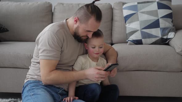 Father showing son funny application on smartphone, spending time together