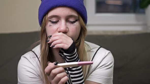 Teenage Girl Looks at the Result of a Pregnancy Test and Cries