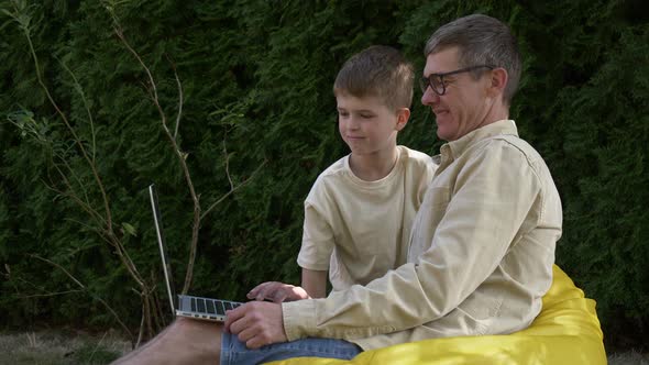 father with son using laptop at outdoor alt