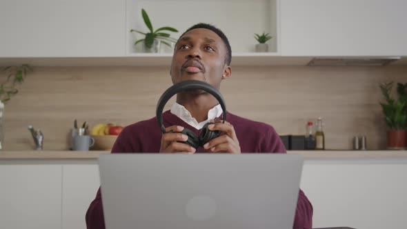 An African American 20s Man is Putting His Headphones Off While Listeting to Someone in Front of Him alt