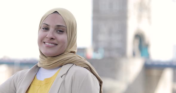 Smiling woman wearing hijab in the city, London, England alt