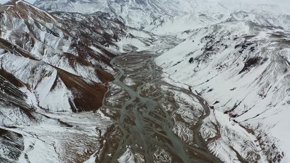 Drone Over Snow Covered Mountains Landscape With Braided Riverbed alt