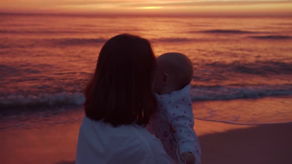 Mom and baby on the background of the sea sunset