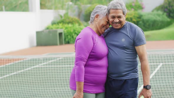 Video of happy biracial senior couple embracing on tennis court alt