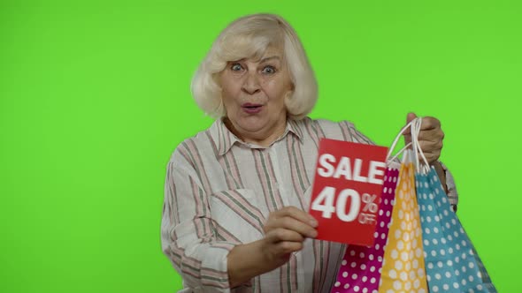 Cheerful Grandmother with Shopping Bags Showing Sale 40 Percent Off Banner Text Advertisement alt