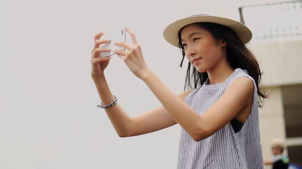 Young Asian woman using smartphones take photos around the Chao Phraya River.