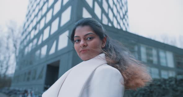 Indian woman looking to the camera outside a building alt