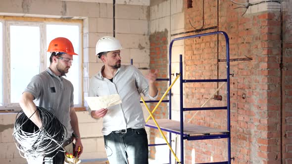 Two men in helmets discuss a project on securities. alt