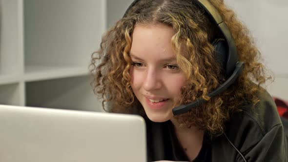 Smiling Teenage Girl Using Laptop and Wearing Headphones