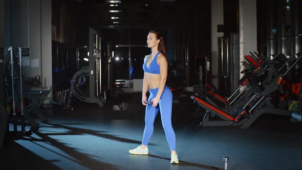 Attractive Woman in Sportswear Doing Squats With Dumbbells in Gym alt