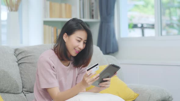 Asian woman using tablet and credit card shopping, female relax feeling happy.