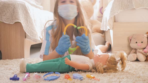 Beautiful Little Girl Playing Doctors with Doll at Home alt