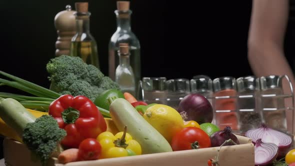 Fresh vegetables, bottles with oil and vinegar, spice jars on the kitchen table alt