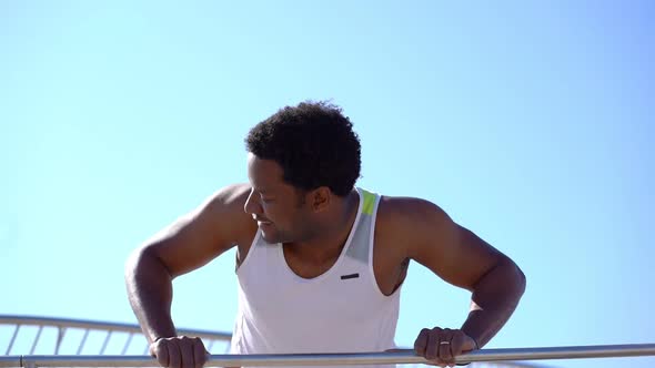 Muscular Man Doing Push Ups on Bar Outdoor alt
