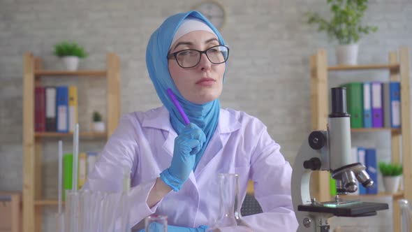 Thoughtful Young Muslim Woman Scientist Chemist in National Scarf Working in the Lab alt